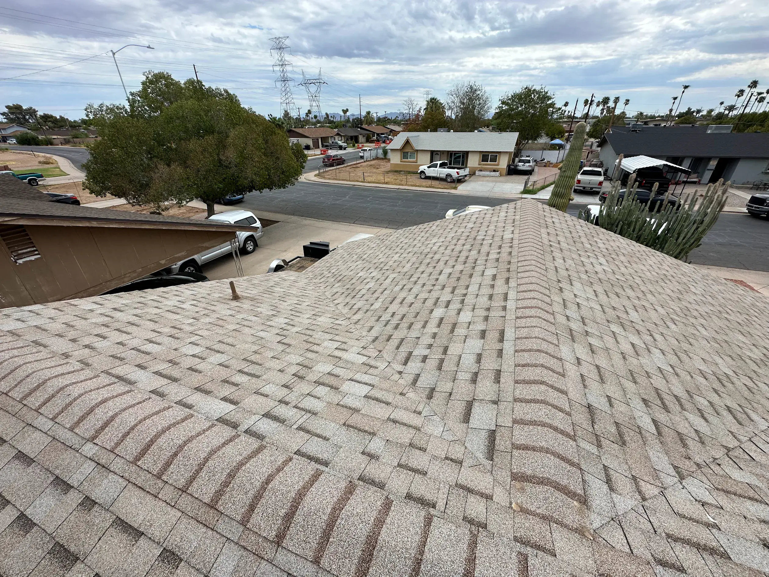 Wide view of a shingle roof with pipe boots and a turbine vent under a cloudy sky